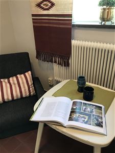 Magazine on a small table with an armchair beside. 
