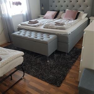 Double bed with bedframe and footrest.