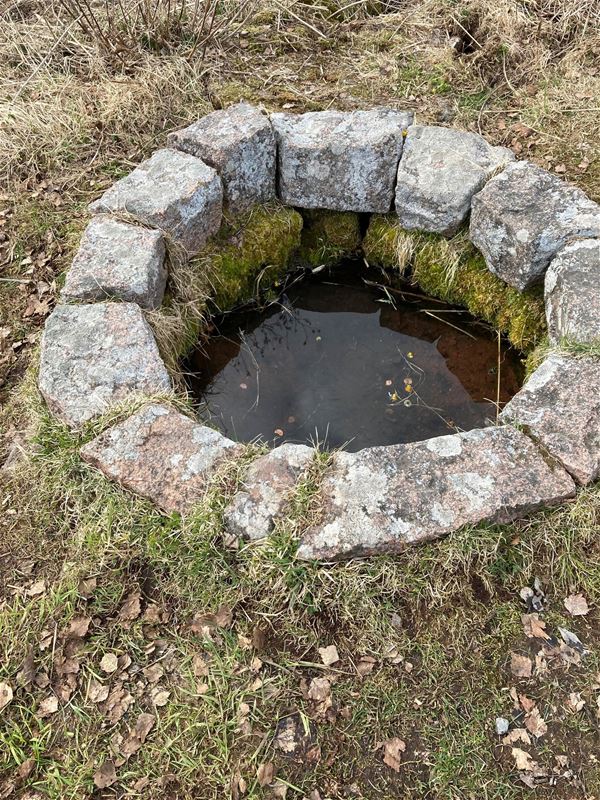Brunn med vatten och stora stenar runt omkring. 