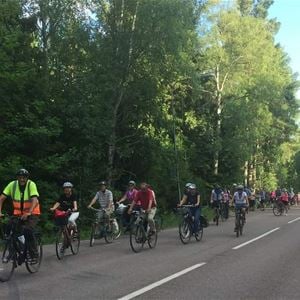  © Per Löfberg, En grupp cyklister cyklar i rad på en väg, grönskande träd i bakgrunden.,