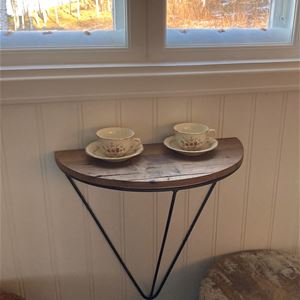Litet bord fast på väggen med kaffekoppar och två pallar intill.