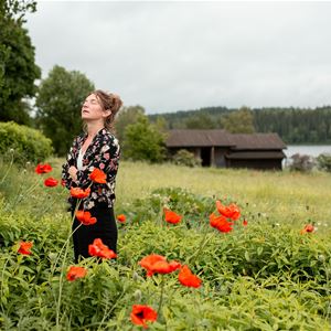 Anna Ihlis står på en sommaräng och blickar mot himlen.