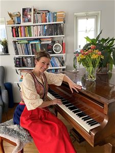 Sonja Aldén sitter vid pianot i Malungsdräkt.