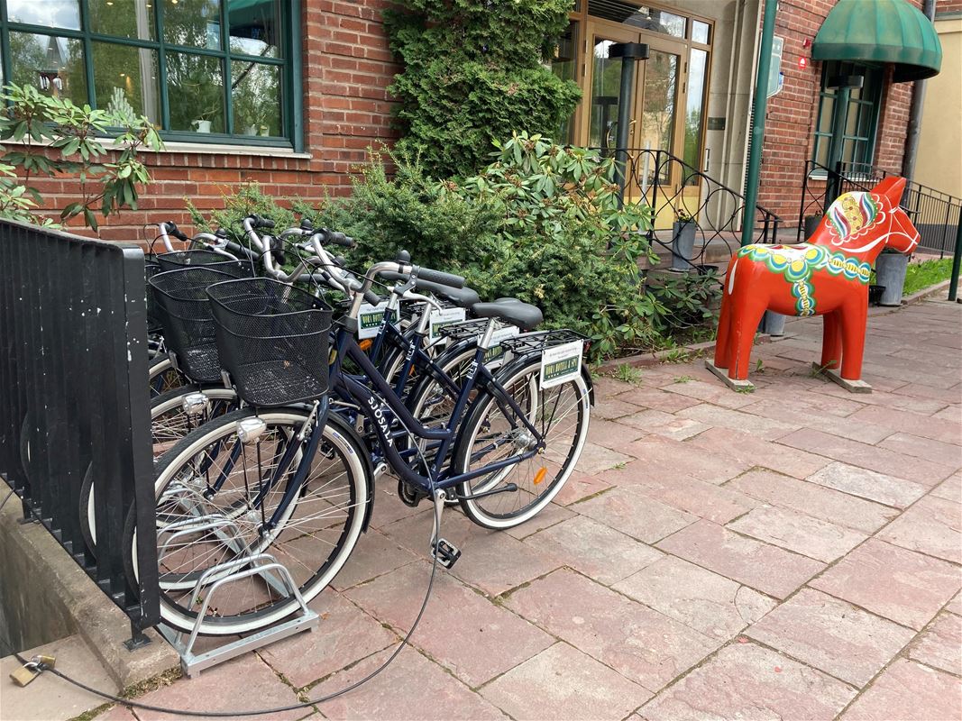 Some bikes in a rack outside the hotel entrance where you can also see a large Dala horse.