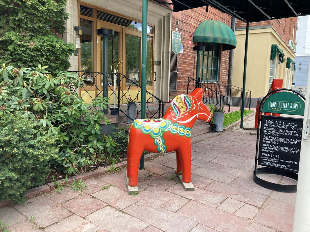 A large Dala horse stands outside the hotel entrance.