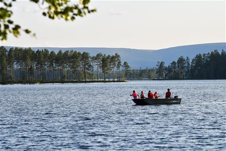 Fem personer sitter i båt och fiskar. 