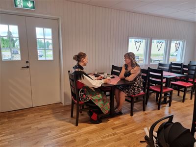 Two ladies are sitting at a table inside having coffee.