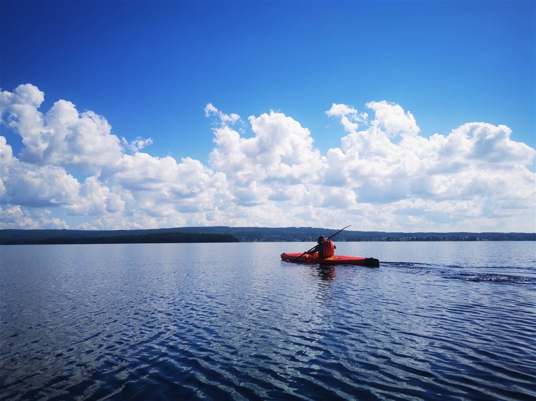 A kayak on the lake with mountains on the horizon and clouds in the blue sky.