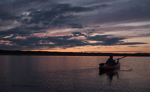 Kajak på sjön med oange kvällshimmel.