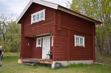 Red log cabin with white windows and door.