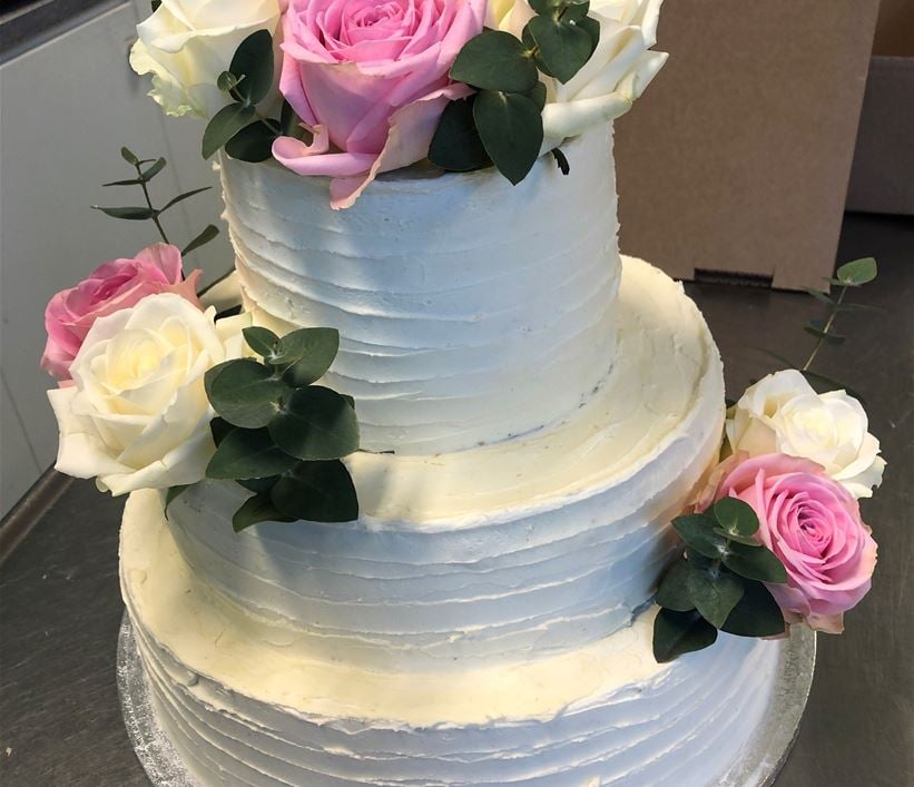 Vit bröllopstårta i tre våningar med rosor