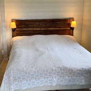 Dubbelsang i ett litet sovrum med vita brädväggar.