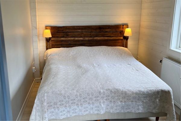 Dubbelsang i ett litet sovrum med vita brädväggar. 