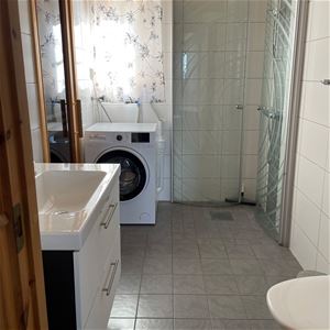 A bathroom with shower and a washing machine.
