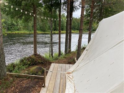 Glamping tent with wooden deck next to the river.