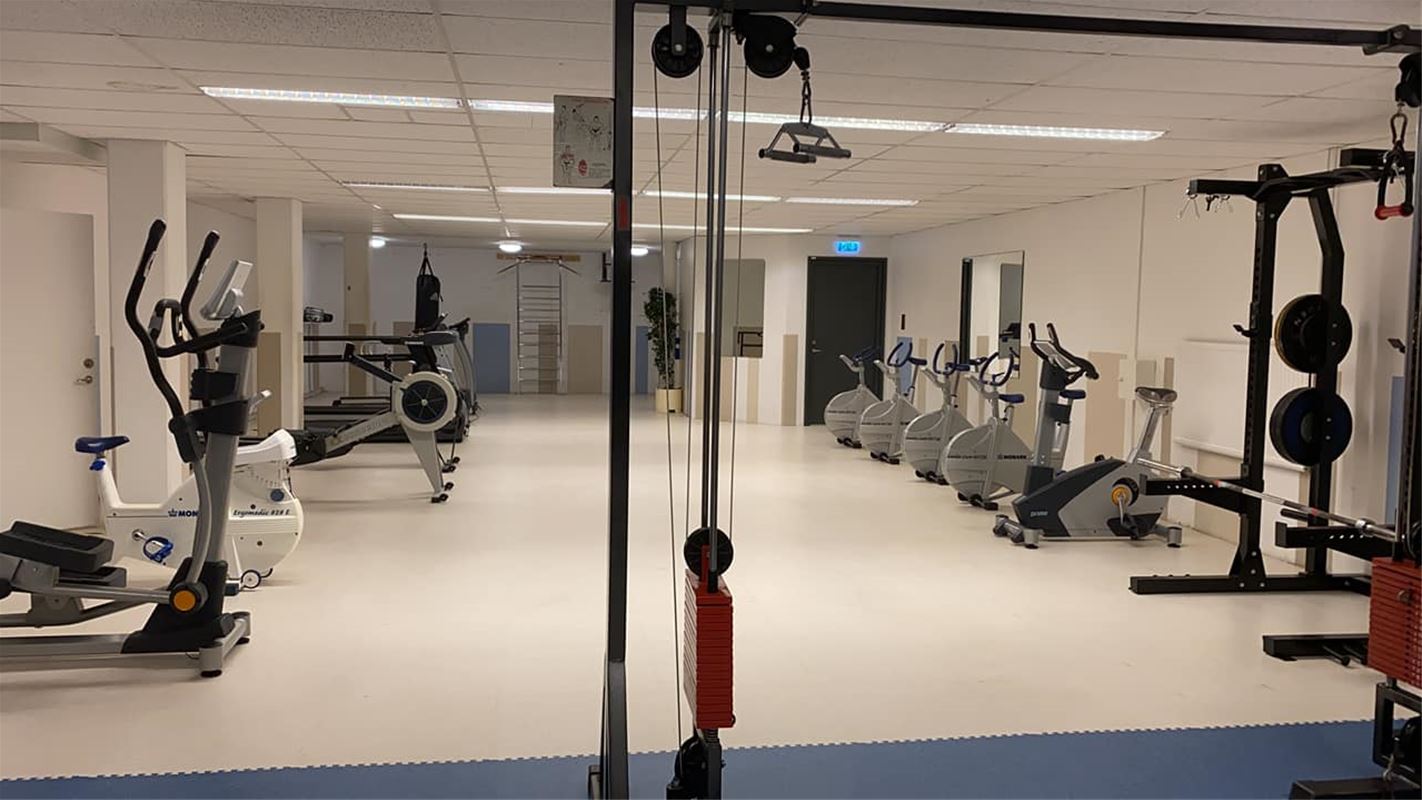 Gymmet med motionscyklar på rad längs väggarna. 