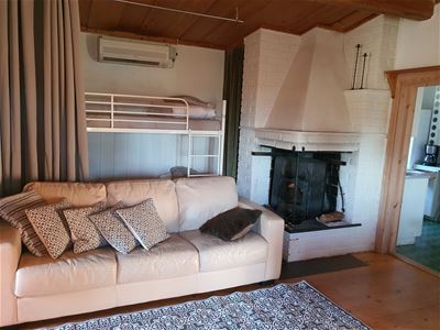 Soffa bredvid en öppen spis och en våningssäng bakom. 