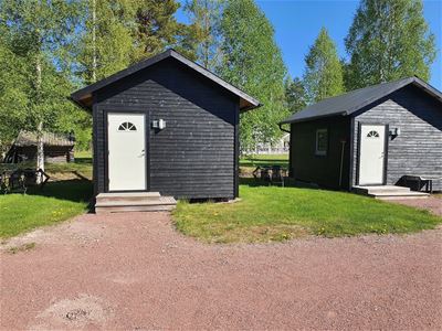 Small blac painted cottages with white doors. 