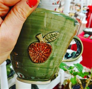 A hand holding a green ceramic mug.