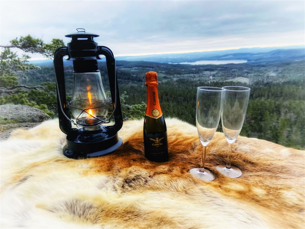 A lantern, a bottle and two glasses are displayed and a nice view behind.