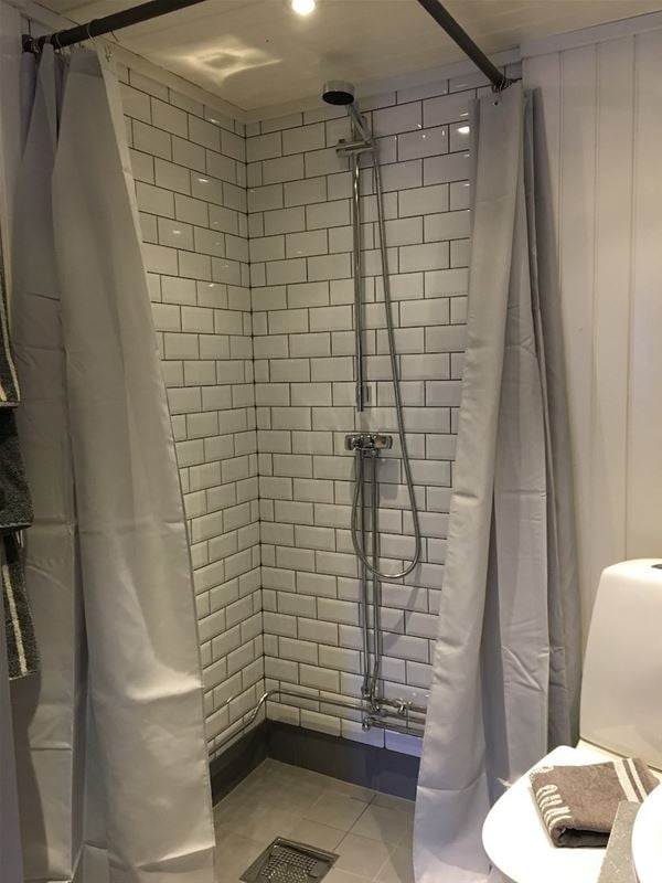 Tiled shower with shower curtains. 