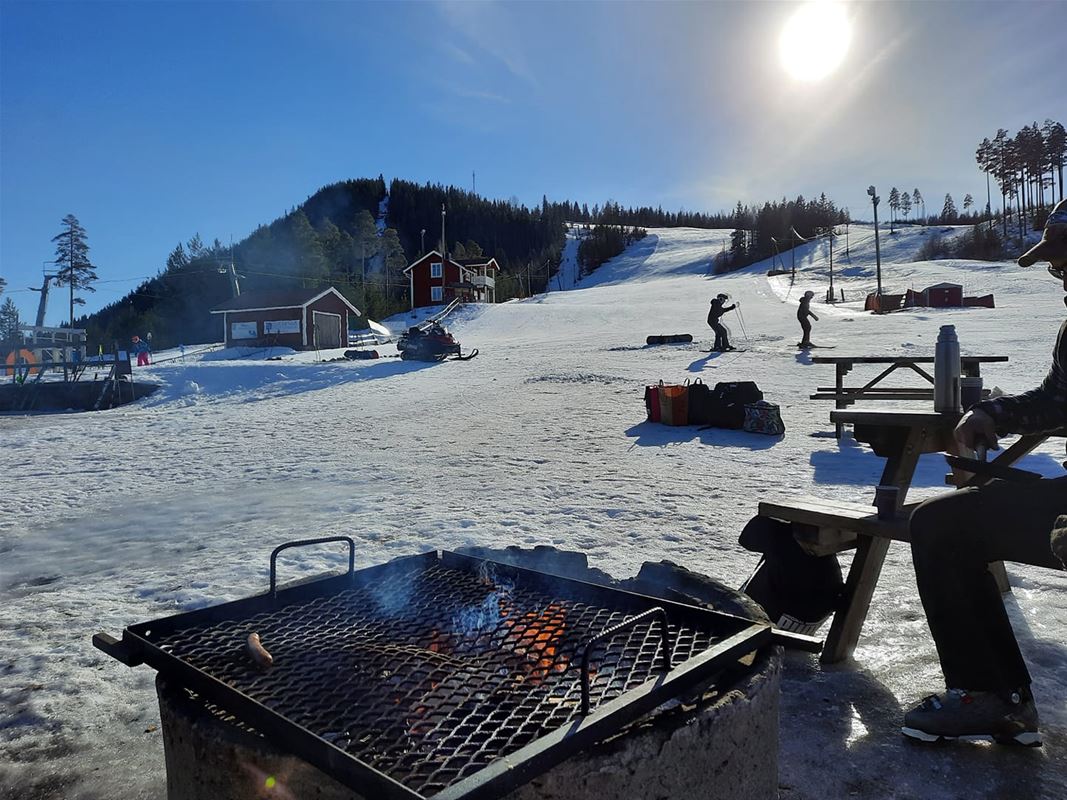 Barbecue area at the bottom of the hill with a view up the hill and blue sky.