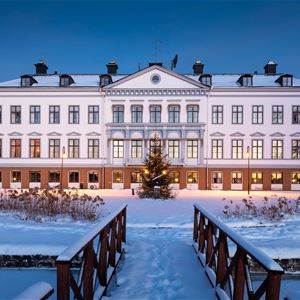 Manuel Fraundorf,  © Gysinge Herrgård, Stor vit upplyst herrgårdsbyggnad i ett vinterlandskap
