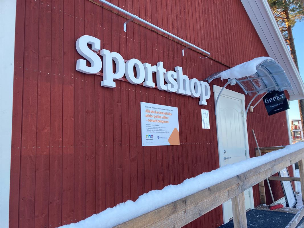 Red wooden house with text Sportshop in white on the outside.