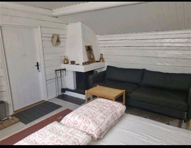 Soffa bredvid en öppen spis och vitmålade timmerväggar.