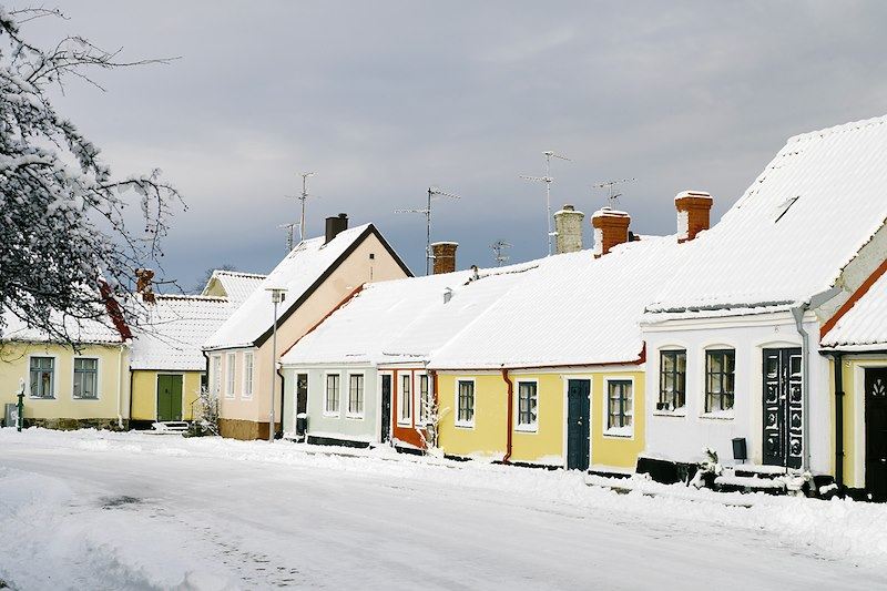 Huslänga med snö på taket och vintrig väg framför