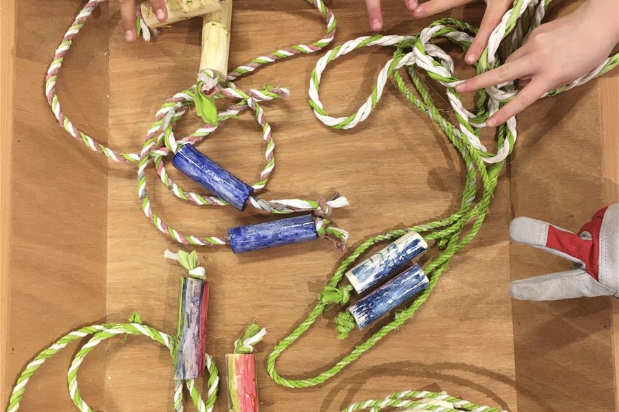 Barnhänder visar egenslagna rep och egenbyggda byggda hopprep i en låda