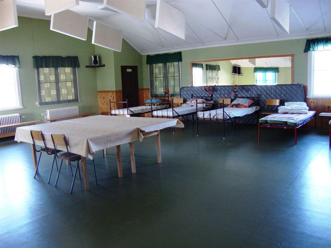 Large room with table in the middle and beds along the sides. 