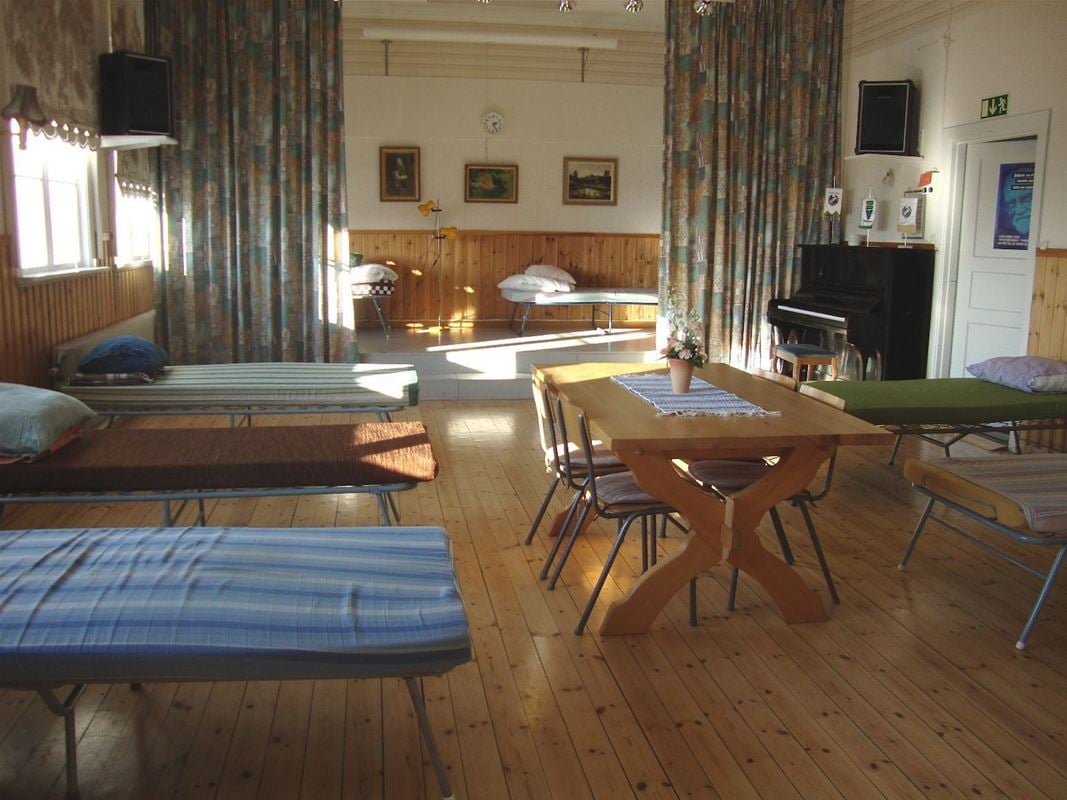Dormitory with beds and a table with chairs in the middle. 