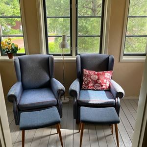 Two armchairs in front of large windows. 