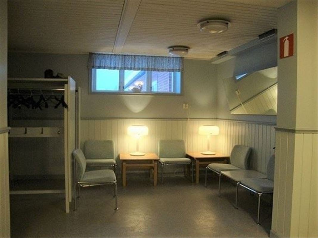 Källarrum med stolar och små bord längs väggarna. 