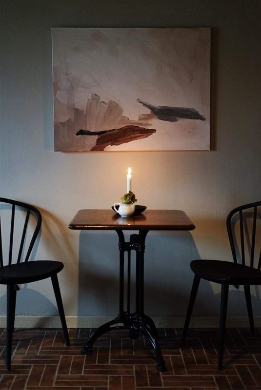 Two chairs and a table in the middle with a candle. 