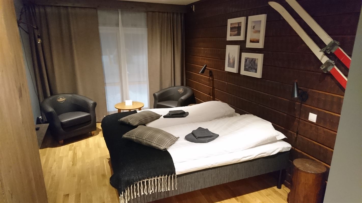 Double bed with white bed linen and a pair of skis mounted on the wall behind the bed.