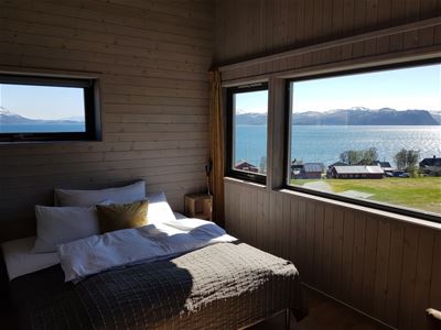 Bedroom with a view of a lake and mountains through large windows