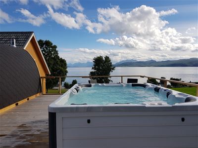 Outdoor hot tub on a terrace with a view of a lake and mountains
