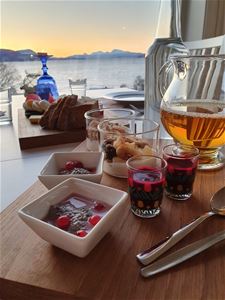 Breakfast table with yoghurt and juice, overlooking mountains and water