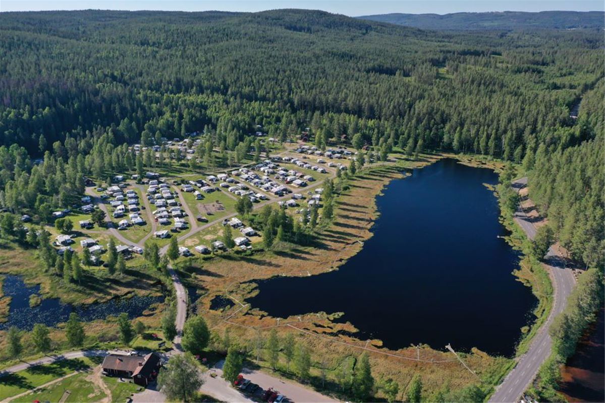 Flygfoto över campingområdet som ligger intill en sjö och med skog runtomkring.
