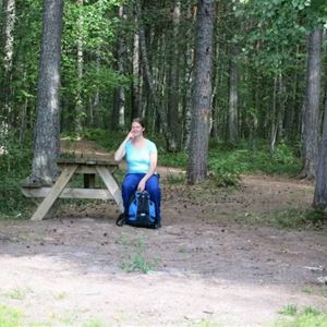 En kvinna vid ett picknickbord i skogen. 