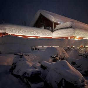 Rött hus med mycket snö på taket.