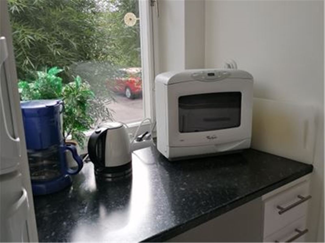 Köksbänk med kaffebryggare, vattenkokare och mikrovågsugn.