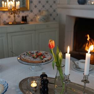 En kaka på ett bord med tulpaner och tända ljus. 