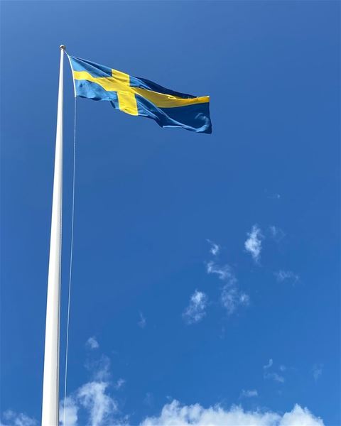 Svensk flagga mot klarblå himmel.  
