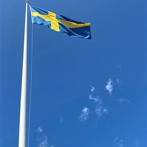 Svensk flagga mot klarblå himmel. 
