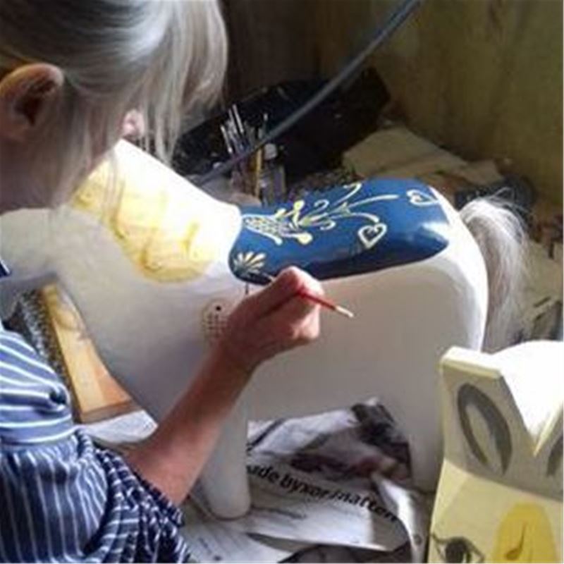 Lady painting a dala-horse.