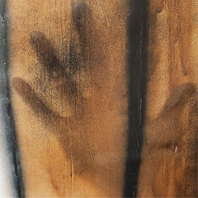 Skugga av hand bakom en brun yta med svarta ränder som ska symbolisera en trävägg