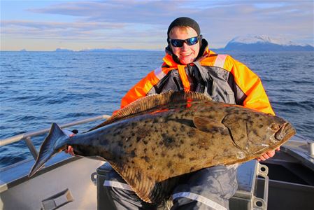 Man holding a halibut on a fishing trip with Explore the Arctic